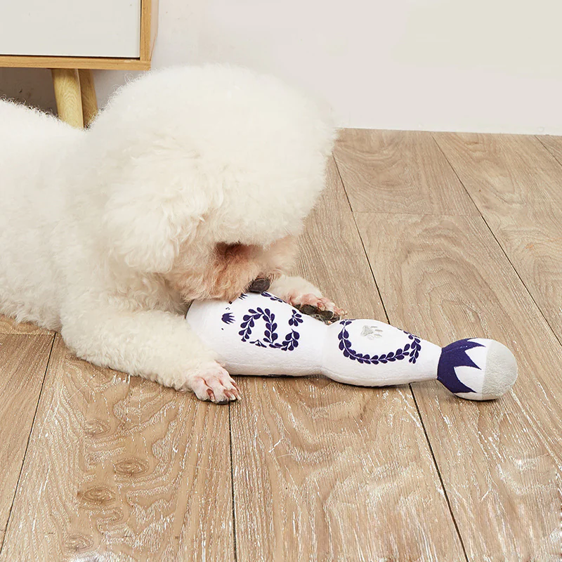 Dog playing with toy shaped like tequila bottle